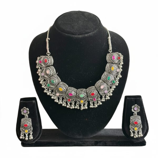 Oxidised silver necklace set with multi-color stones and matching earrings displayed on a black jewellery stand.