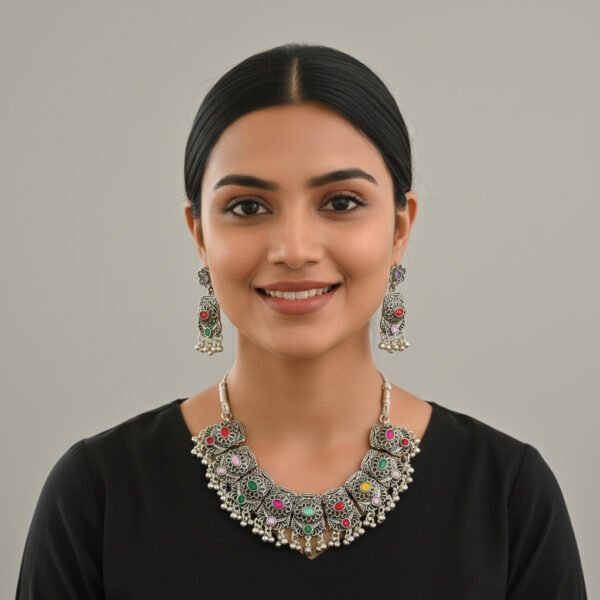 Oxidised silver necklace set with multi-color stones and matching earrings displayed on a black jewellery stand.